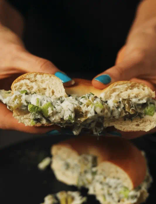 Bagel filled with dill, pickles, and Violife dairy-free cream cheese