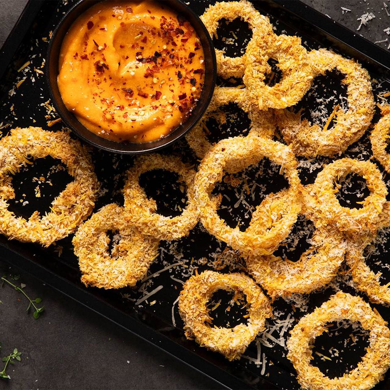 Crispy onion rings coated in breadcrumbs and dairy free cheese accompanied by a dip made with cream cheese, chili flakes and ground paprika for dipping.
