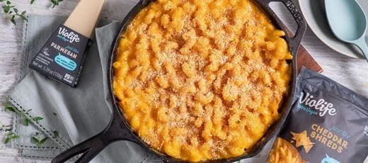 A black cast-iron skillet filled with mac ‘n’ cheese made with Violife dairy free cheese, plant butter and cavatappi pasta.