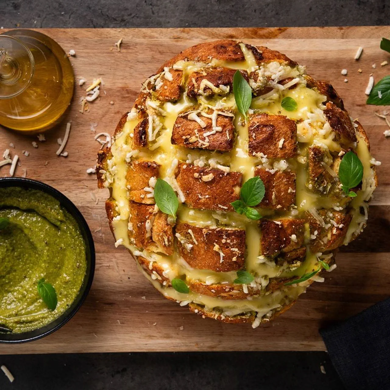 A round loaf of bread sliced in a crisscross “hedgehog” pattern and filled with melted dairy free cheese, plant butter, garlic and herbs.