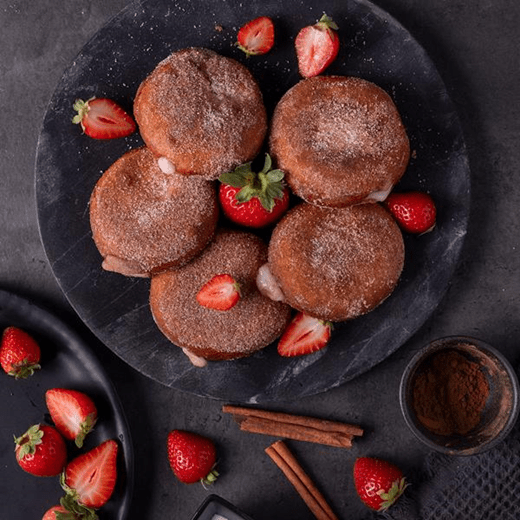 Donut holes - small, round pastries filled with supreme cream cheese that are golden brown and evenly coated with a layer of granulated or powdered sugar.