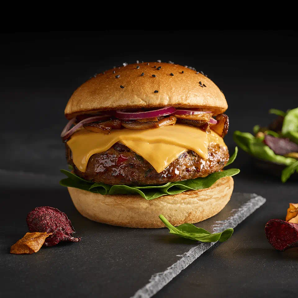 Burger végétal avec des tranches Violife, l'alternative 100 % végétale au fromage, sur fond sombre