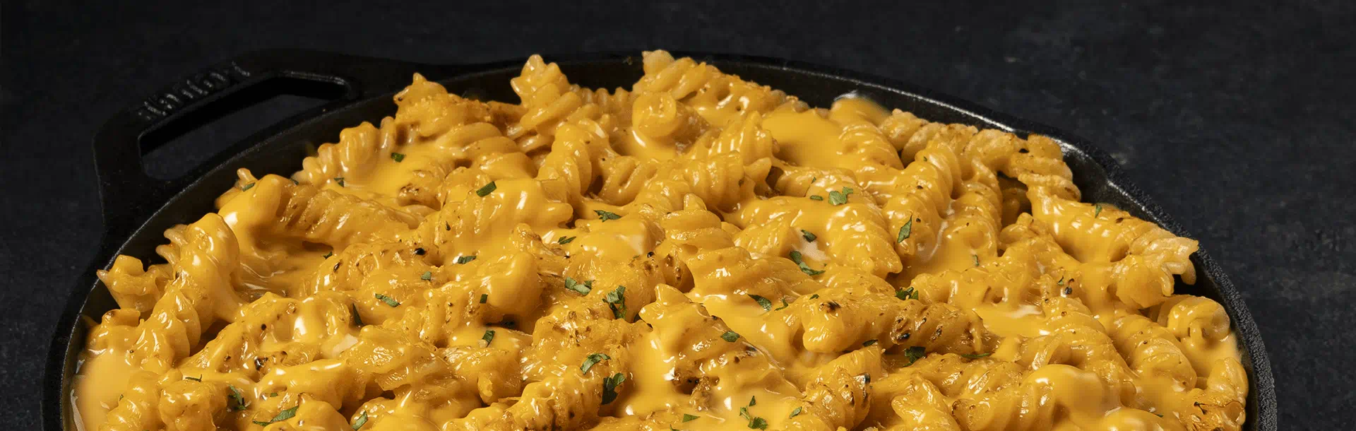 Fusilli dans une poêle, nappés d’une sauce  réalisée avec les râpés Violife alternative 100% végétale 