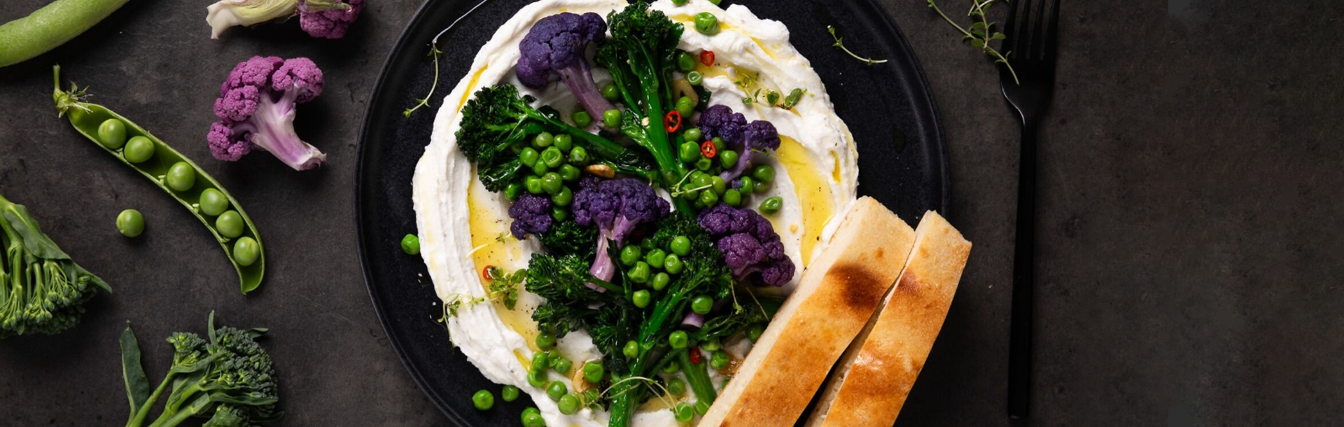 Assiette de dip d'alternative végétale au fromage, garnie de chou‑fleur violet, broccolini, petits pois, piment émincé et filet d’huile d’olive